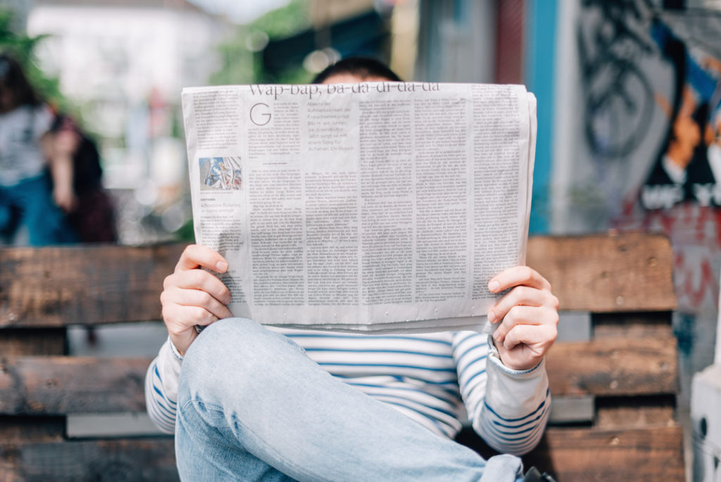 someone reading a newspaper with a headline about a cannabis business in it